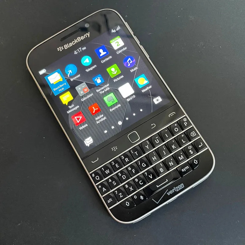 A BlackBerry Classic phone lying on the table, list of applications displayed on the screen.